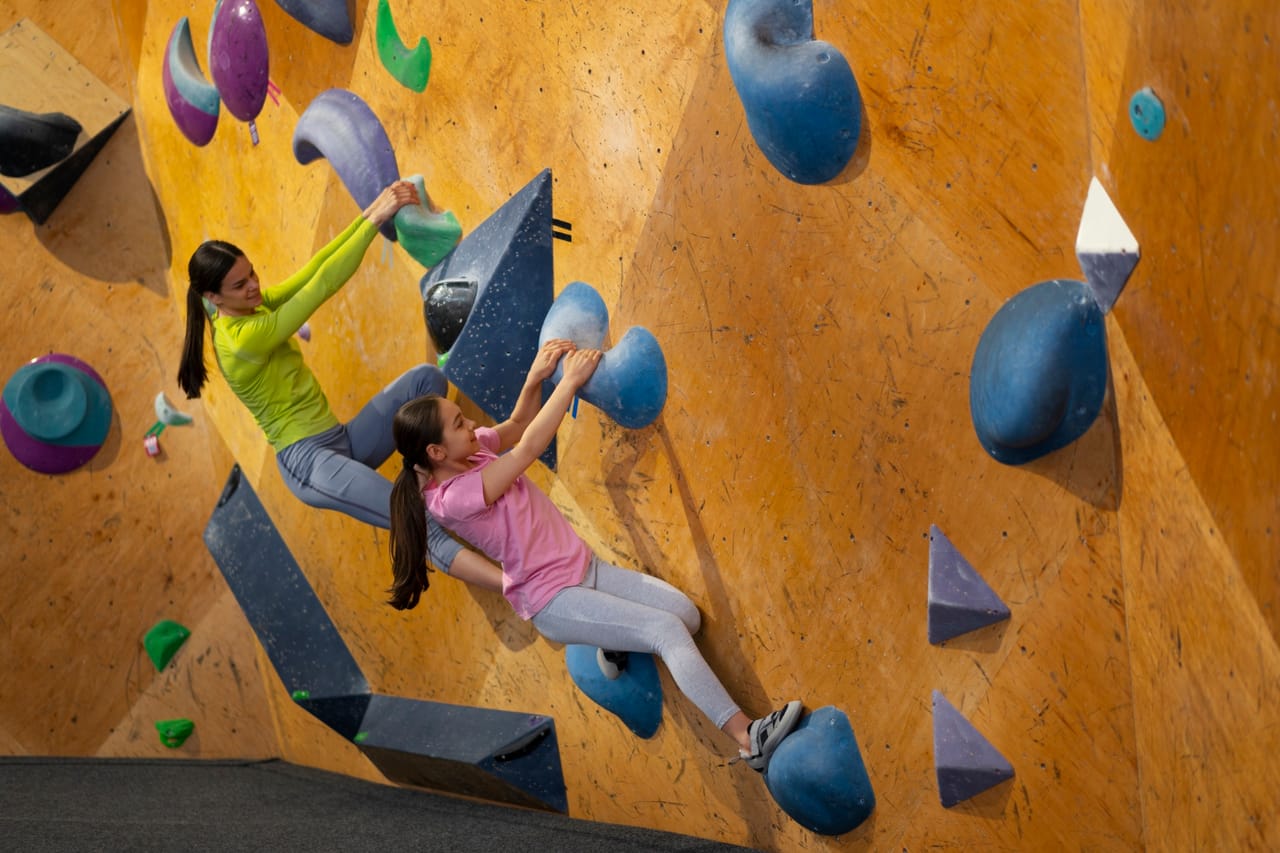 Kinder bouldern in der Boulderhalle an bunten Griffen